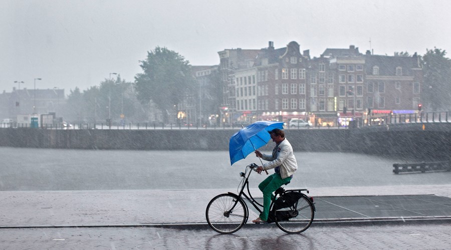 man fietst met blauwe paraplu in de regen