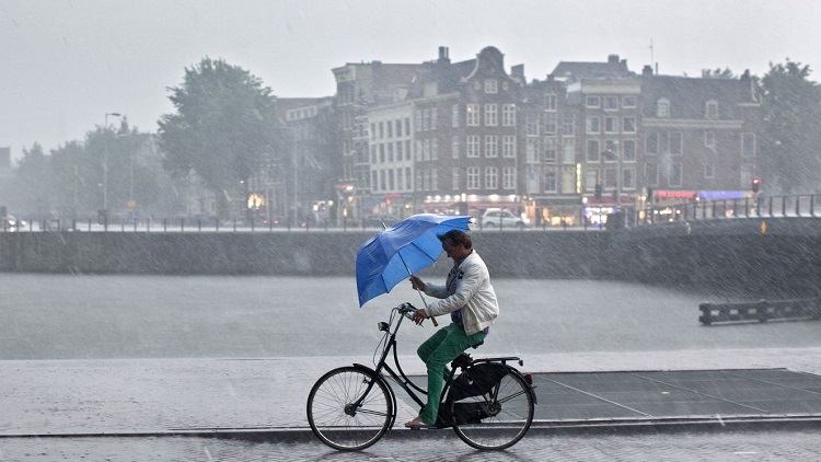 man fietst door de regen oosterdok