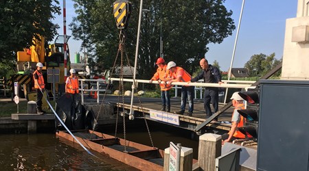 Medewerkers van Waternet plaatsen de stalen dam bij de Westveense brug in Woerdense Verlaat op 4 juli 2018.