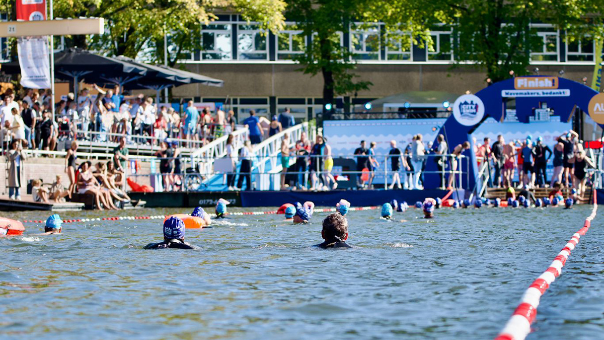 Mensen zwemmen in de gracht tijdens Amsterdam City Swim.jpg
