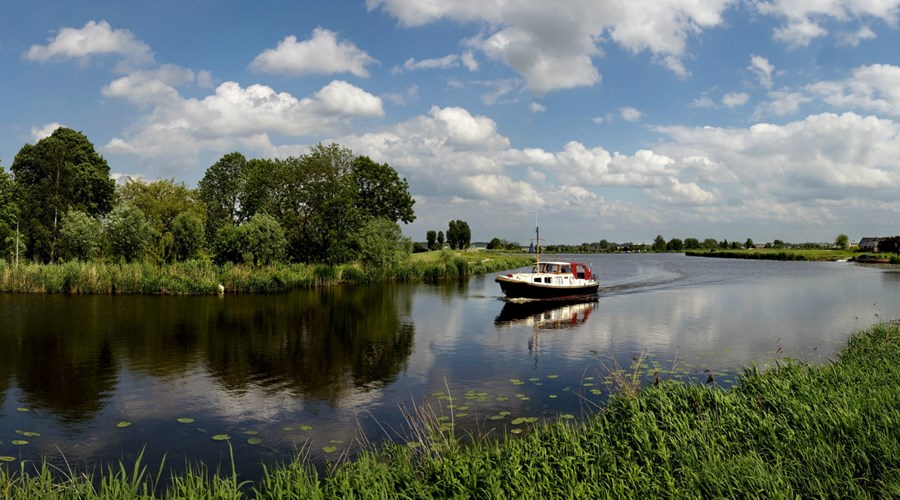 Een bootje vaart over een rivier in de polder Ronde Hoep.