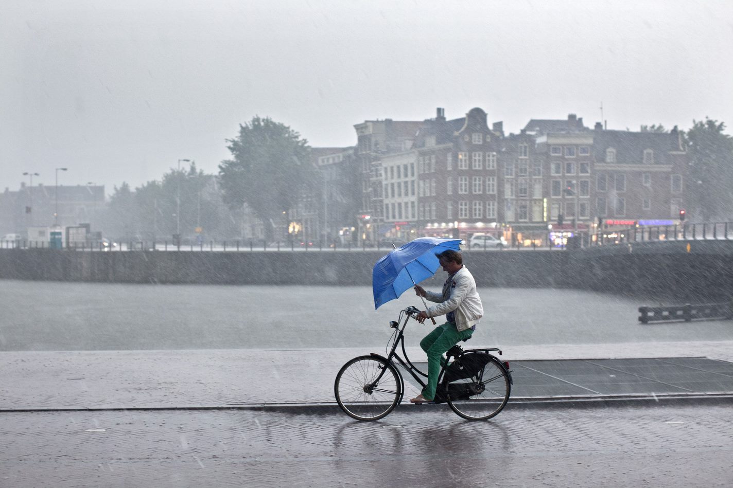 man fietst door regen met paraplu.jpg