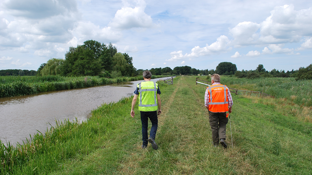 Twee mannen lopen over een dijk.jpg